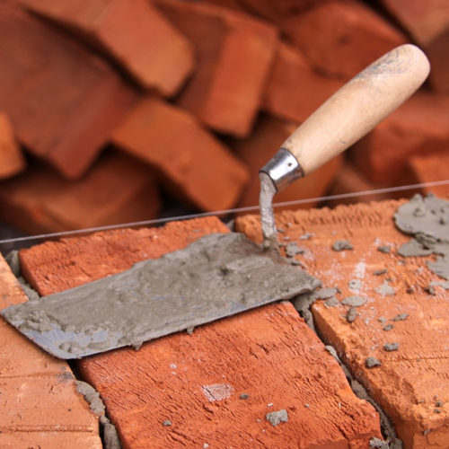 Masonry craftsperson applying mortar to brick